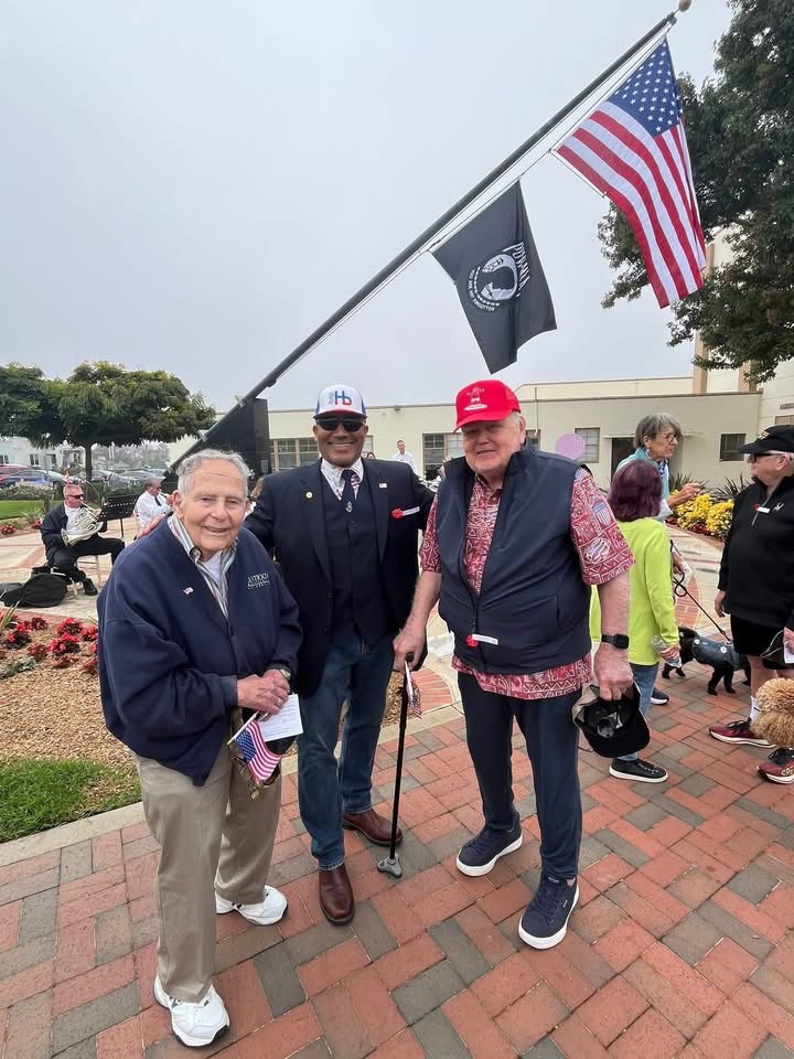 Ray Jackson and community members standing outdoors near an American flag.