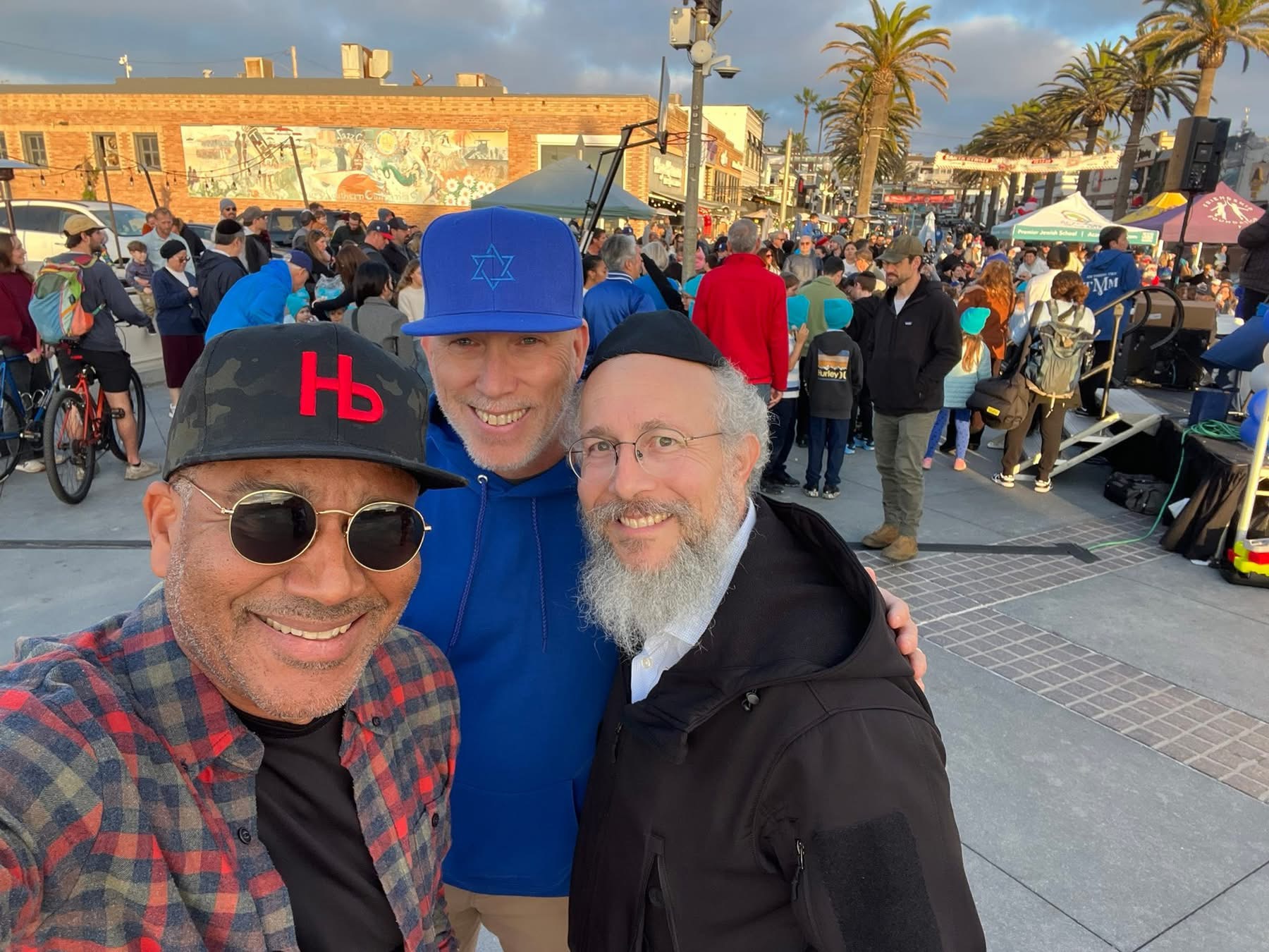 Ray Jackson taking a selfie with two men at an outdoor street festival.