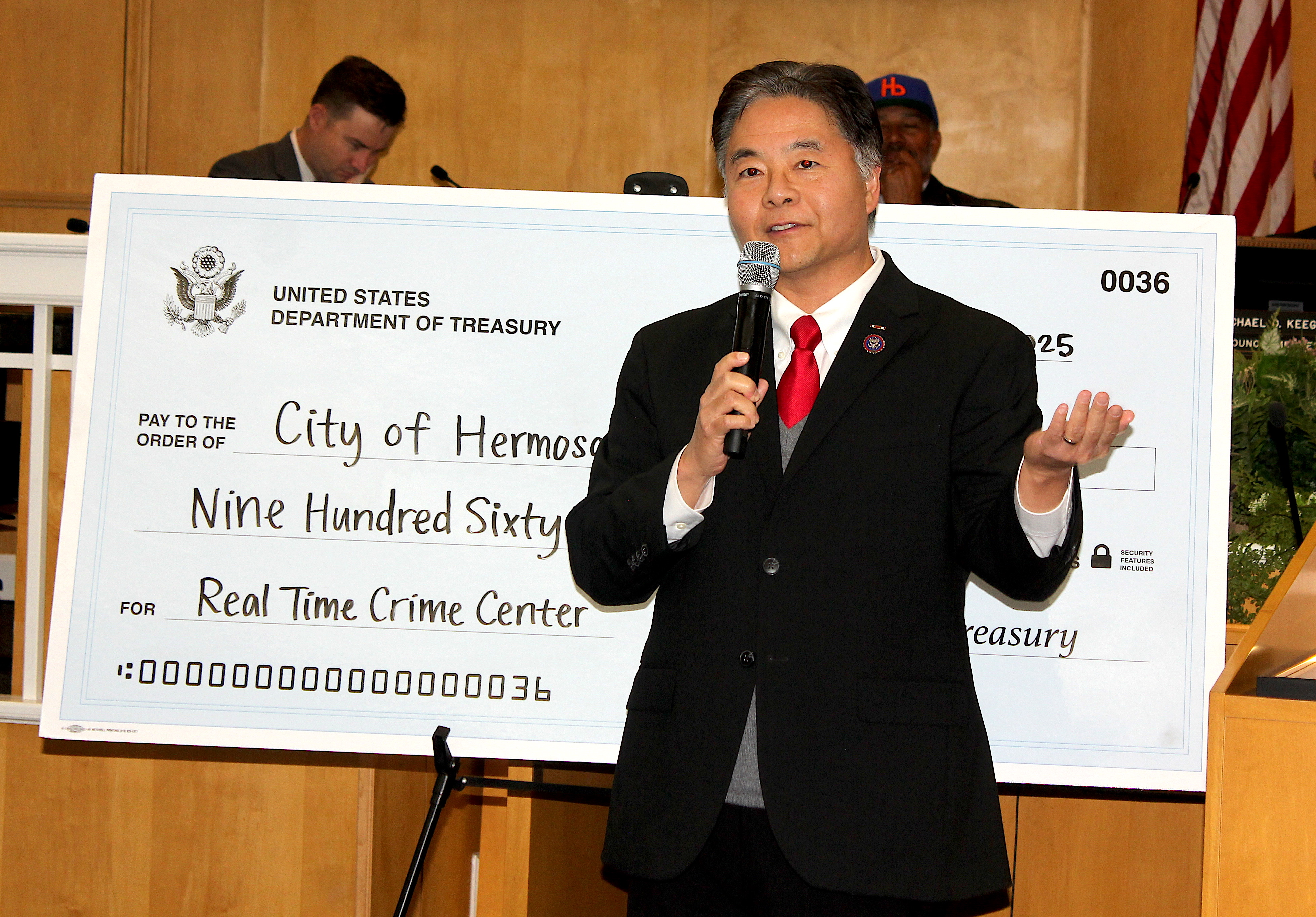 A man speaking at a podium next to a U.S. Treasury check made out to the City of Hermosa Beach for the Real-Time Crime Center.